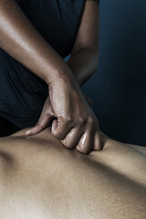 Oily hands of a brunette masseuse applying pressure on a patient's back