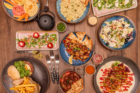 Set of colorful muby healthy food plates with cane meatballs, salad, tomatoes, hummus of various flavors on wooden table