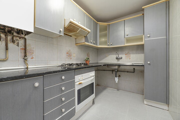 A used fitted kitchen with gray cabinets and white handles