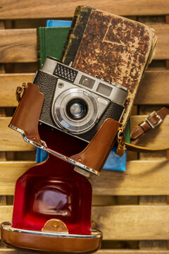 Vintage style still life with old camera with leather case on old books