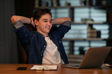 Obraz premium Excited young guy entrepreneur looking at laptop screen, smiling