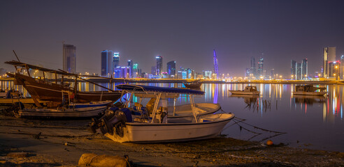 Motor boats on the shore of Persian Gulf with illuminated downtown in the background, Manama, Bahrain