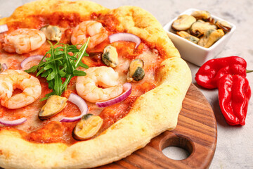 Wooden board with tasty seafood pizza on grunge background