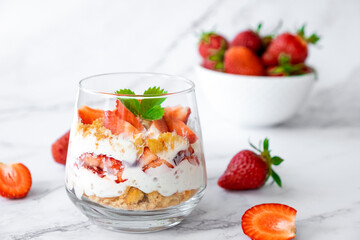 Strawberry trifle dessert with custard, cake crumb and fresh strawberry in glass on marble. Recipe of simple layered dessert with fresh berry and jam. Lactose free cheesecake, vegan dessert tiramisu.
