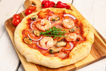 Board with tasty seafood pizza on light wooden background