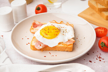 Delicious sandwich with fried egg and bacon on light background