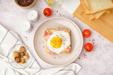 Delicious sandwich with fried egg and bacon on light background