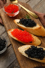 Tasty bruschettas with red and black caviar on wooden background