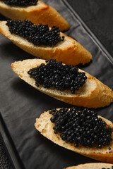 Tasty bruschettas with black caviar on dark background