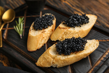 Tasty bruschettas with black caviar on wooden background