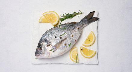 Raw whole dorado fish on white board and spices for cooking, top view on white table