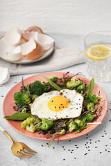 Plate with tasty fried egg and salad on table