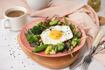 Plate with tasty fried egg and salad on light background