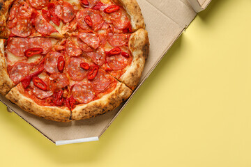 Cardboard box with delicious pepperoni pizza on yellow background