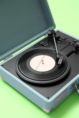 Record player with vinyl disk on green background, closeup