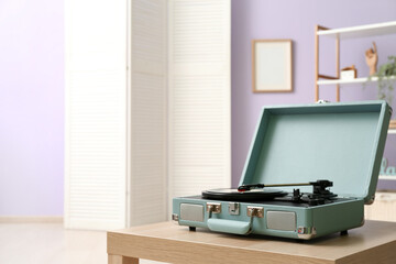 Record player with vinyl disk on table in room