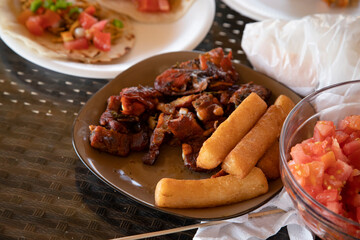 Plate of barbecued ribs with yucca and tomatoes cut at outdoor table