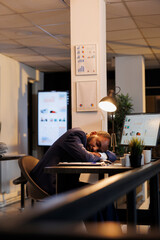 Hardworking entrepreneur falling asleep on table in startup office after finishing financial report. Workaholic executive manager working overtime at workspace, planning company investment strategy