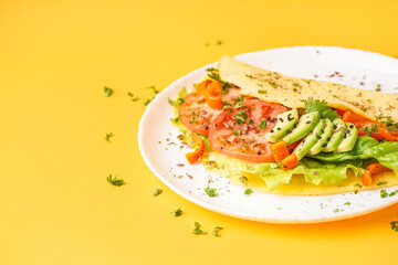 Tasty omelet with vegetables on yellow background