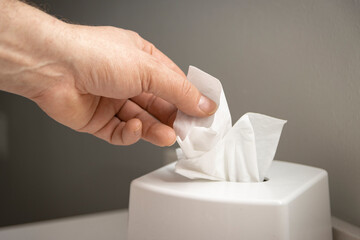 Hand pulling facial tissue from dispenser