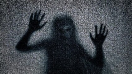 The eerie silhouette of a veiled ghost trapped inside an old retro analog television, trying to break the screen, struggling to escape, mixed with static noise.
