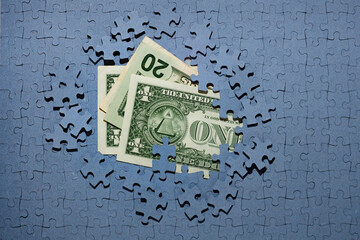 US dollar banknotes under an unfinished puzzle. Economic crisis, inflation, hidden assets, sanctions, unfriendly currencies