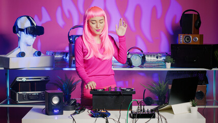 Artist with pink hair dancing and having fun in nightclub, mixing eletronic sound with techno using professional mixer. Dj performer playing remix using audio equipment, performing at musical event