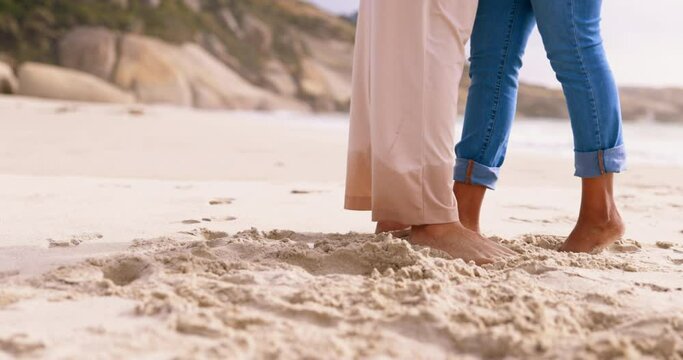 Couple, love and feet in beach sand outdoor while romantic and together on vacation or holiday. Happy man and a woman leg up for kiss at sea for time on a date, care and freedom or travel adventure