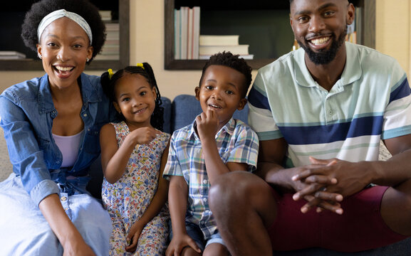 Portrait Of Smiling African American Parents And Children Sitting On Sofa In Living Room At Home