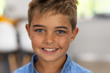 Closeup portrait of caucasian cute boy with gray eyes and blond hair smiling at home, copy space