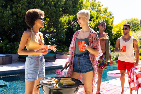 Happy diverse group of friends having pool party, barbecuing together in garden