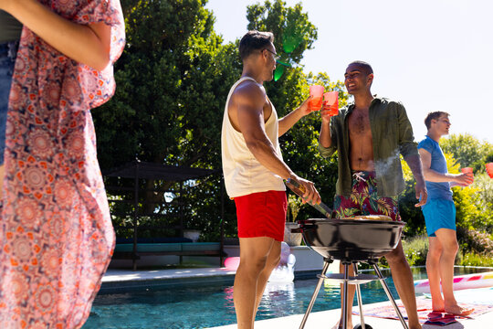 Happy diverse group of friends having pool party, barbecuing together in garden