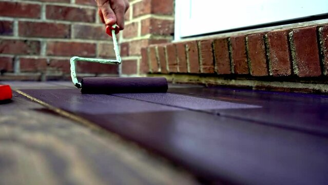 Close up from hand painting deck with paint roller with brown color