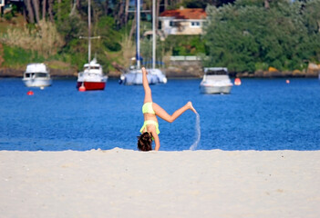 A girl playing pirouettes in the sand of a beach. Holiday concept © TopMicrobialStock
