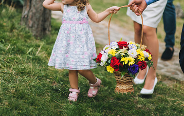 A little girl, a child with a wicker basket with flowers goes outdoors on a birthday, at a wedding in the park. Photography, holiday.