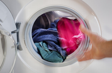 Person Hand wirft Wäsche Wäschestück in Waschmaschine zum Waschen befüllen Waschgang