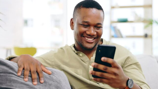 Black man, phone and smile on sofa for social media, communication or networking in living room at home. Happy African American male relaxing on couch with mobile smartphone for browsing or chatting