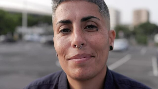 Authentic portrait of gay lesbian woman smiling on camera outdoor - Lgbt nonbinary people concept