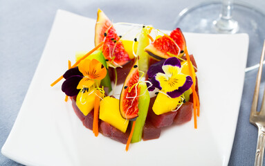 Delicious seafood tartare prepared with raw tuna garnished with cucumber, figs and flowers..