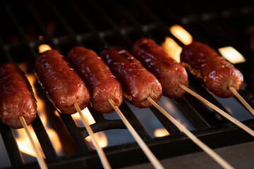 Sausages on a spit. Close-up of sausages on grill with bamboo sticks with space for text.