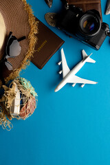 Airplane model, sunglasses, passport and camera on blue background with copy space