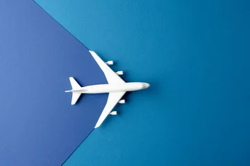 Poster Close up of white airplane model on blue background with copy space © vectorfusionart