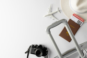 Airplane model, straw hat, passport, camera and suitcase on white background with copy space