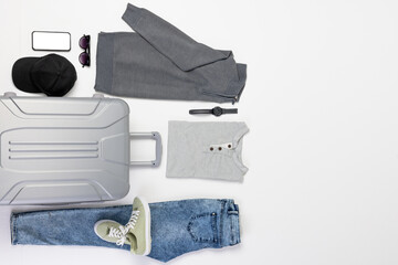 Suitcase, clothes, sunglasses, watch and smartphone with copy space on screen on white background