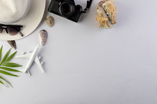 Airplane model, straw hat, sunglasses, camera and seashells on white background with copy space