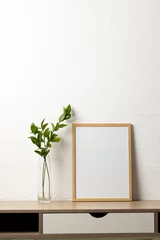 Foto op Plexiglas Historisch gebouw Vertical of empty wooden frame with copy space and plant on table against white wall