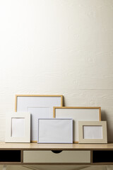 Vertical of five various empty frames with copy space on table against white wall