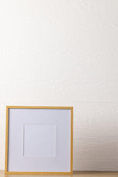 Vertical of empty wooden frame with copy space on table against white wall