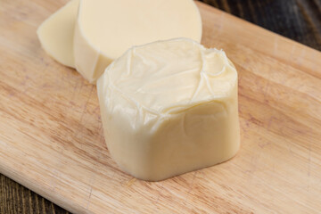 Soft cheese sliced into thick chunks on a cutting board