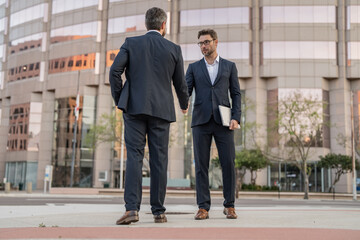 full length of two business men in suit are handshaking in agreement. photo of two business men